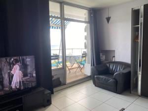 a living room with a tv and a couch and a window at Bleu Caraibe studio in Schœlcher