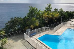 a swimming pool with a view of the ocean at Bleu Caraibe studio in Schœlcher
