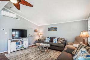 a living room with a couch and a tv at Sea Glass Shack in Kill Devil Hills