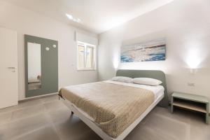 a white bedroom with a bed and a window at Appartamenti Mancaversa in Marina di Mancaversa