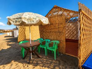 a table and chairs with an umbrella on the beach at Espace Azaimi in Tarîfa