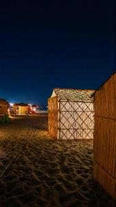 a wooden building on a sandy beach at night at Espace Azaimi in Tarîfa
