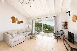 a living room with a couch and a tv at Villa Bougainvillea in Vlachopoulátika