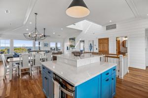a kitchen and dining room with blue cabinets and a table at Knot for Sail in Duck