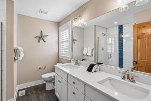 a bathroom with two sinks and a toilet and a mirror at Knot for Sail in Duck +82 photos