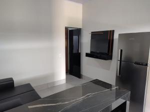a kitchen with a refrigerator and a tv on the wall at Espaço Aconchegante e Moderno in Primavera do Leste