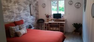 a bedroom with a red bed and a brick wall at Le Mimosa in Cricquebœuf