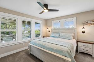 a bedroom with a bed with a ceiling fan and windows at Sanctuary in Duck