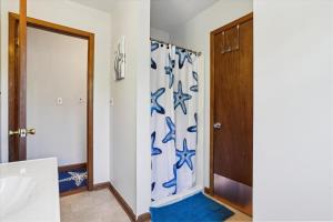 a bathroom with a shower with a blue and white shower curtain at Doris's Day in Duck +41 photos