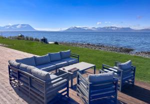 a couch and two chairs and a table and water at Lyngen Experience Lodge in Nord-Lenangen