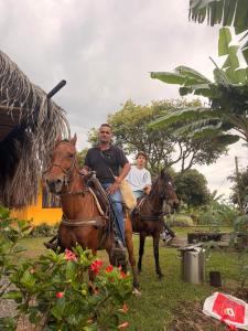 two men are riding horses in the grass at Hotel Cabañas Del Quindio in Filandia