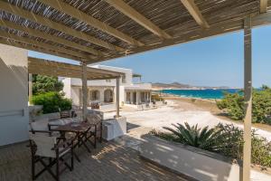 an outdoor patio with a table and chairs and the beach at Iliovasilema Studios in Mytakas