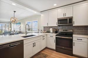 a kitchen with white cabinets and a sink and a microwave at Tidewater Star Unit 2i in Duck