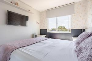 a bedroom with a white bed and a window at Apto com conforto que você precisa. in Goiânia +36 photos