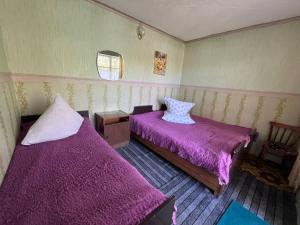 two beds in a room with purple sheets at уют in Cholpon-Ata