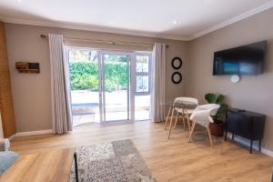 a living room with a television and a table and chairs at The Palm Suites in Meadowridge