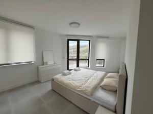 a white bedroom with a bed and a window at View of the forest in Veliko Tŭrnovo