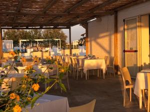 a group of tables and chairs with white tables and flowers at Riva Sweet Home in Giovinazzo