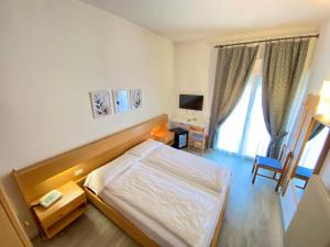 ein Schlafzimmer mit Bett, Schreibtisch und Fernseher in der Unterkunft Hotel Alberello - Varone in Riva del Garda