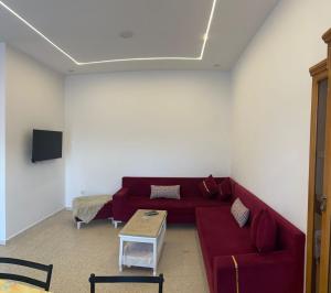 a living room with a red couch and a table at Dar Samir in Awlād ‘Umar