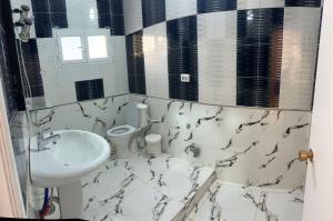 a white bathroom with a sink and a toilet at Dar Samir in Awlād ‘Umar