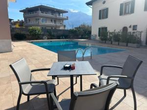 ein Tisch und Stühle neben einem Schwimmbecken in der Unterkunft Hotel Alberello - Varone in Riva del Garda