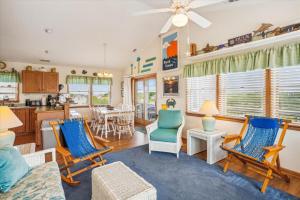 a living room with blue chairs and a kitchen at Duck Views in Duck