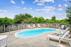 a swimming pool with lounge chairs and a fence at Duck Views in Duck