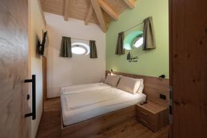 a small bedroom with a bed and two windows at Palazzo Tamanini in Calceranica al Lago