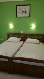 2 Betten in einem Zimmer mit grüner Wand in der Unterkunft Kogeros in Agios Georgios Pagon