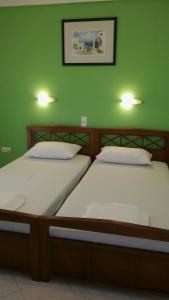 two beds in a room with a green wall at Kogeros in Agios Georgios Pagon