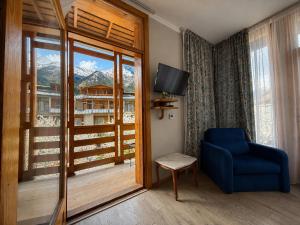 a room with a blue chair and a large window at Hotel Old Seti in Mestia