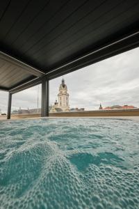 a swimming pool with a clock tower in the background at Palatinus Grand Hotel in Pécs +64 photos