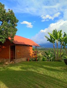 a house with a red roof on a green field at Hotel Cabañas Del Quindio in Filandia