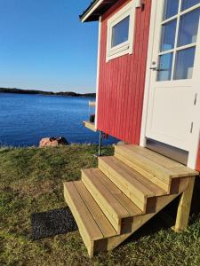 a red and white house with a wooden staircase next to the water at Your cottege by the sea in Saltvik