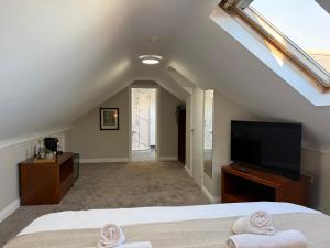 a bedroom with a bed and a flat screen tv at All Seasons Guesthouse in Belfast