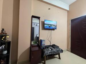 a living room with a tv on the wall at Triveni Stays in Jorhat