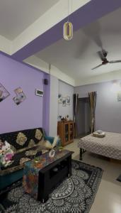 a living room with purple walls and a couch at Triveni Stays in Jorhat