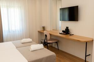a room with two beds and a desk with a television at JB Hotel in Sarandë
