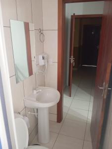 a bathroom with a sink and a mirror and a toilet at Hotel Maciel in Ponta Grossa