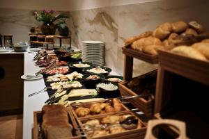 a buffet line with different types of bread and pastries at Palatinus Grand Hotel in Pécs