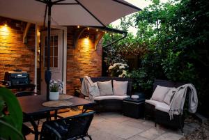 a patio with a table and chairs and an umbrella at Beautiful New Forest Hideaway in West Wellow