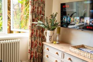 a vase with flowers on a dresser next to a window at Beautiful New Forest Hideaway in West Wellow +33 photos
