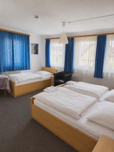 three beds in a room with blue curtains at Hotel Ochsen in Leonberg