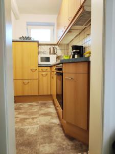 a small kitchen with wooden cabinets and a microwave at Unterkunft Ramser in Bad Eilsen