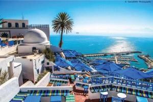 a view of a resort with blue umbrellas and the ocean at Mediterranean Breeze Studio in Sidi Bou Saïd