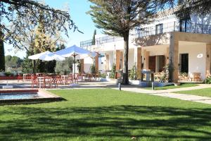 un patio con mesas y sombrillas frente a un edificio en Hotel Bodega El Juncal en Ronda