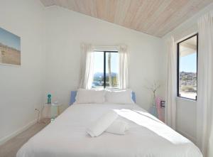 a white bedroom with a large white bed with a window at The Giddyup in Pioneertown
