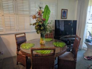 a dining room table with a vase of flowers on it at Kihei Kai Nani 112 in Kihei