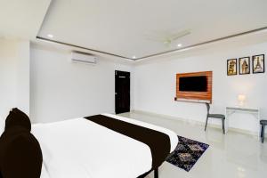 a white bedroom with a bed and a chair at Hotel O Inn In Town in Sangāreddi